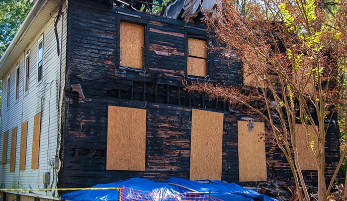 fire damaged house with board-up windows